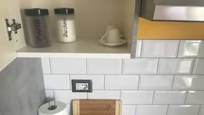 A kitchen with white tiles, a coffee maker, a sugar container, and a wooden box. - Loft relaxation in the hills (Lazio)