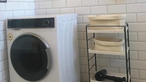 A compact laundry area with a front-loading washing machine, a metal drying rack, and a tiled floor with a geometric pattern. - Loft relaxation in the hills (Lazio)