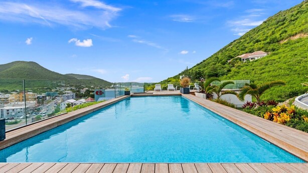 A rooftop pool with clear blue water, surrounded by wooden decking and potted plants. - A134 - Panoramic View of the Lagoon (Sint Maarten)