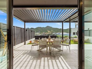 An outdoor patio with a table set for four, a pergola overhead, and a view of mountains in the background. - A101 - Outstanding Lagoon View & Garden (Sint Maarten)