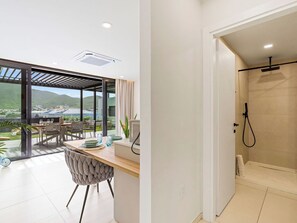 A modern interior with a dining area, a shower, and a view of the outdoors. - A101 - Outstanding Lagoon View & Garden (Sint Maarten)