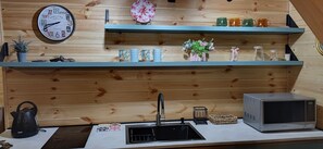 Een koelkast, een waterkoker, kookgerei, borden en bestek