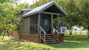 En lille træhytte med veranda, trapper og en klimaanlæg.