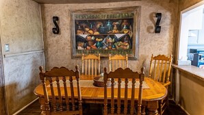 Een eethoek met een houten tafel en stoelen, een schilderij aan de muur en een bord met het nummer 7.