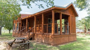 A wooden cabin with a porch, a staircase, and picnic tables.