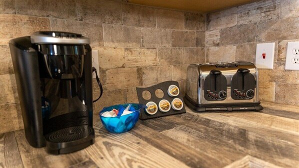A kitchen with a coffee maker, toaster, and a bowl of muffins.