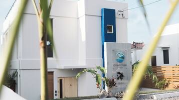 A modern building with a blue accent wall, a sign reading "Ocean View - Ishiigaki," and a wooden door.