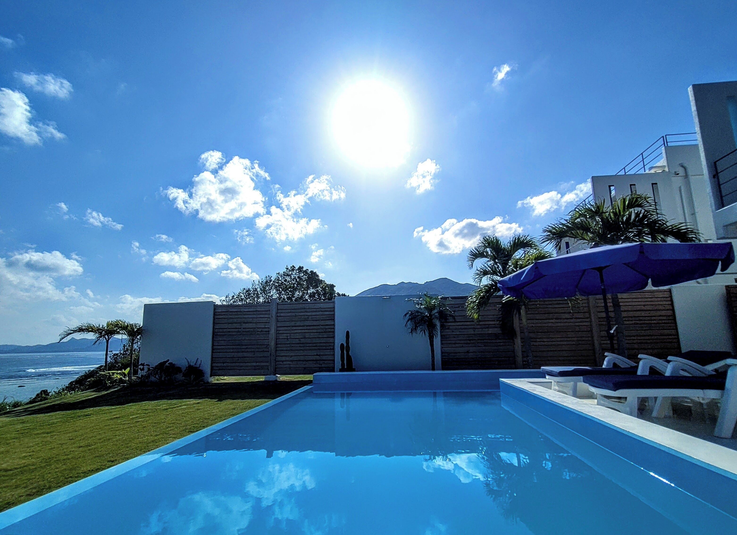 A modern pool area with a clear view of the ocean and mountains in the background.