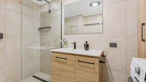 Bathroom features a glass-enclosed shower, vanity with drawers, and a mirror.