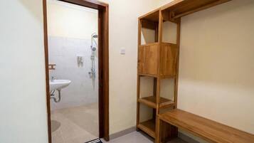 A bathroom with a wooden shelf unit, a sink, and a shower.