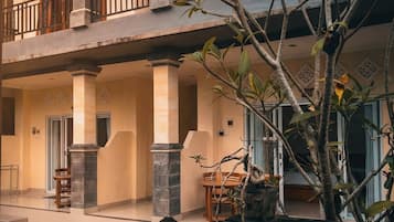 Un edificio de dos pisos con un balcón, columnas y una estatua de una deidad.