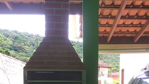 Un horno de ladrillo al aire libre con chimenea, paredes verdes y suelo de baldosas.
