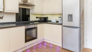 A modern kitchen with white cabinets, a stainless steel range hood, a built-in oven, a microwave, a refrigerator, and under-cabinet lighting. - Drake St, close to York station and York Centre (York)
