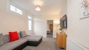A modern living room with a grey sectional sofa, a wooden cabinet, and a TV mounted on the wall. - Drake St, close to York station and York Centre (York)