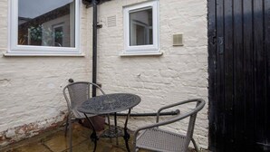 A small patio with a metal table and two wicker chairs, a white brick wall, and a black door. - Drake St, close to York station and York Centre (York)
