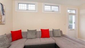 A modern living room with a sectional sofa, two windows, and a door. - Drake St, close to York station and York Centre (York)
