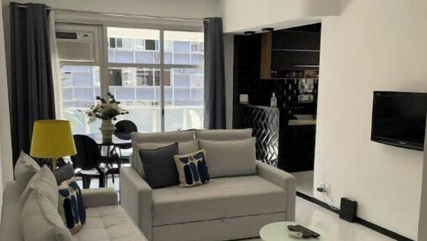 A modern living room with a sofa, a small round table, and a TV mounted on the wall. - Precioso Apartamento con Terraza y Piscina (Ipanema Rio de Janeiro)