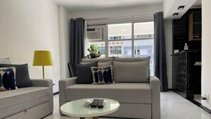 A modern living room with a grey sofa, a round coffee table, and a yellow floor lamp. - Precioso Apartamento con Terraza y Piscina (Ipanema Rio de Janeiro)