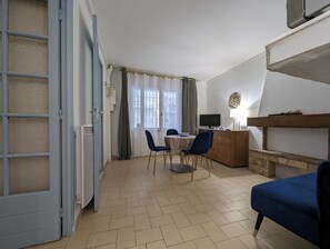 A room with a dining table, chairs, a TV, a fireplace, and a blue sofa. - Apart. BleuThau, Marseillan Village (Marseillan)