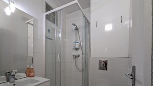 Ein modernes Badezimmer mit einer Duschkabine, einem weißen Waschbecken und einer Toilette.
