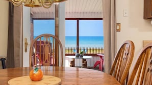 Ein Holzespeisesaal mit einer Kürbisdekoration, Holzstühle und Blick auf das Meer durch große Fenster.