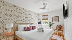 A neatly arranged bedroom with a bed, bedside table, lamp, and a chair.