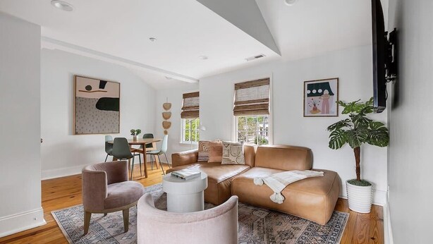 A modern living room with a leather sofa, a round coffee table, and a large potted plant.