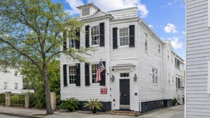 A white two-story building with black shutters, a flag, and a 'FD' sign.