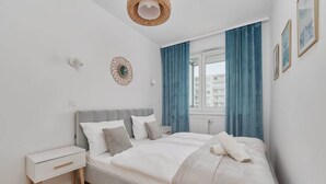 Ein modernes Schlafzimmer mit Bett, Nachttisch und einem Fenster mit Vorhängen.