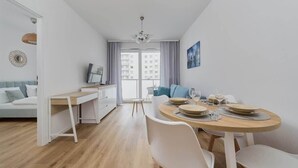 Eine moderne Wohnung mit Essbereich, einer Couch, einem Fernseher und Blick auf die Stadt.