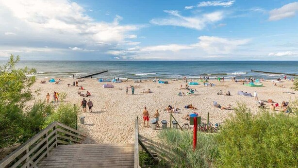 A beach with a wooden staircase leading down to the sand, a pier extending into the water, and people relaxing on the beach. - Modern Apartment | Close to the Beach, Parking (Sianozety)