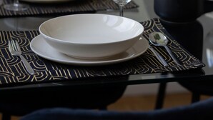 A dining table set with plates, cutlery, and wine glasses, with a decorative plant in the background. - Spacious Apartment in the Center | Balcony and Workspace (Warszawa)