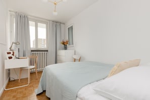 Relax in a peaceful bedroom with a neatly made bed, dresser, and desk by the window.