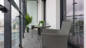 Un balcon agrémenté de meubles en osier, d’une petite table et de plantes en pot.