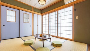 Une pièce de style japonais traditionnel, avec un sol recouvert de tatamis, des paravents shoji et une table basse en tatami, agrémentée de coussins.