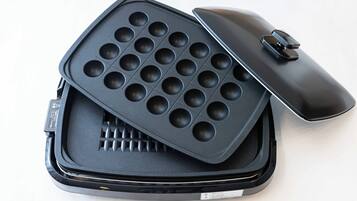 Una plancha para gofres con tapa y asa, colocada dentro de un estuche.