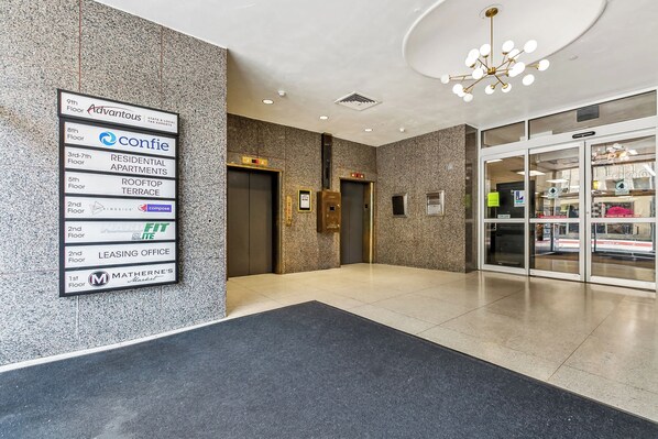 A hotel lobby with a sign indicating various floors and amenities, including residential apartments, a rooftop terrace, and a leasing office.