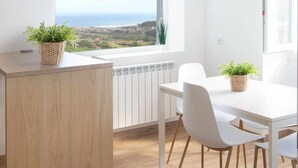 Una cocina moderna con una isla de madera, sillas blancas y plantas en macetas.