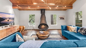 Un salon moderne avec une cheminée, des canapés bleus et un plafond en bois.