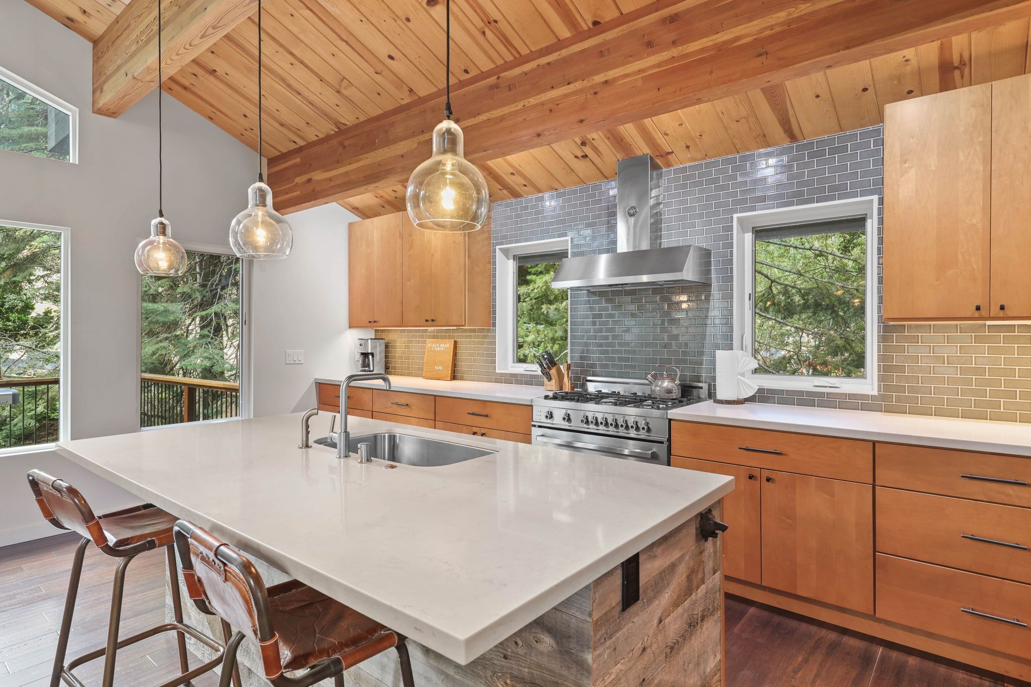 A modern kitchen with a large island, wooden cabinets, and a gas stove.