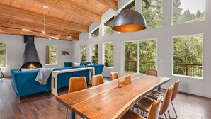 Un vaste espace de vie comprenant une grande table à manger en bois, un canapé bleu et une cheminée.