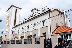 A building with a prominent clock tower, a series of windows, and a gated entrance. - Konak Stella (Belgrade)