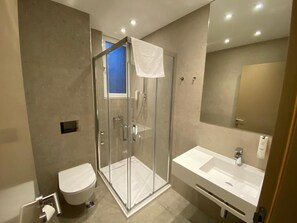 A modern bathroom with a glass-enclosed shower, a toilet, and a sink with a mirror. - Konak Stella (Belgrade)