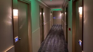 A hotel hallway with carpeted floors, doors with light switches, and a ceiling fan. - Konak Stella (Belgrade)