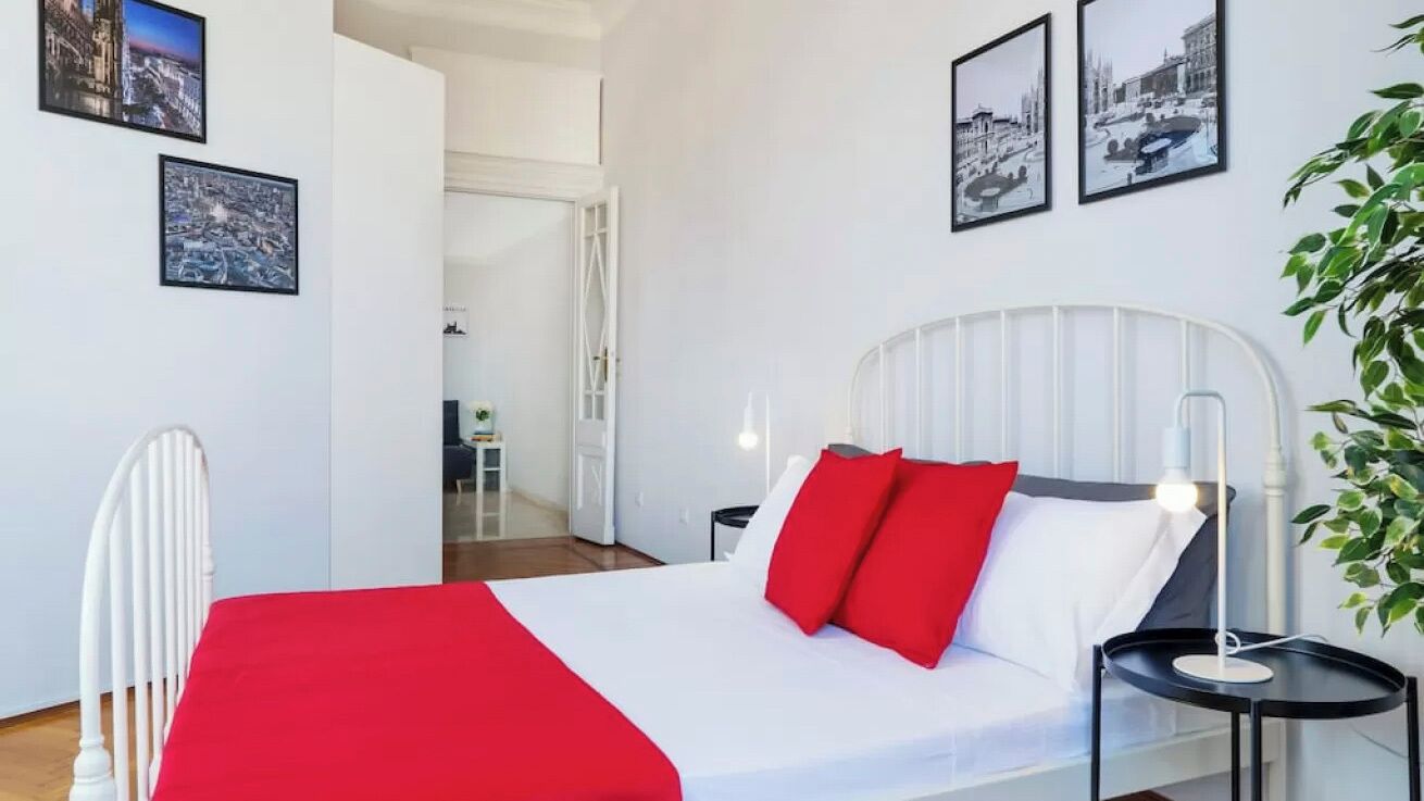Habitación de hotel con cama, paredes blancas y cuadros enmarcados.