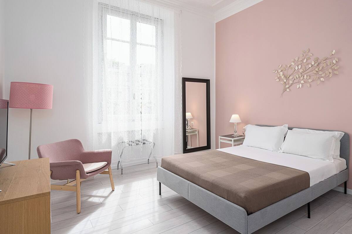 A modern bedroom with a large bed, bedside tables, a chair, and a desk.