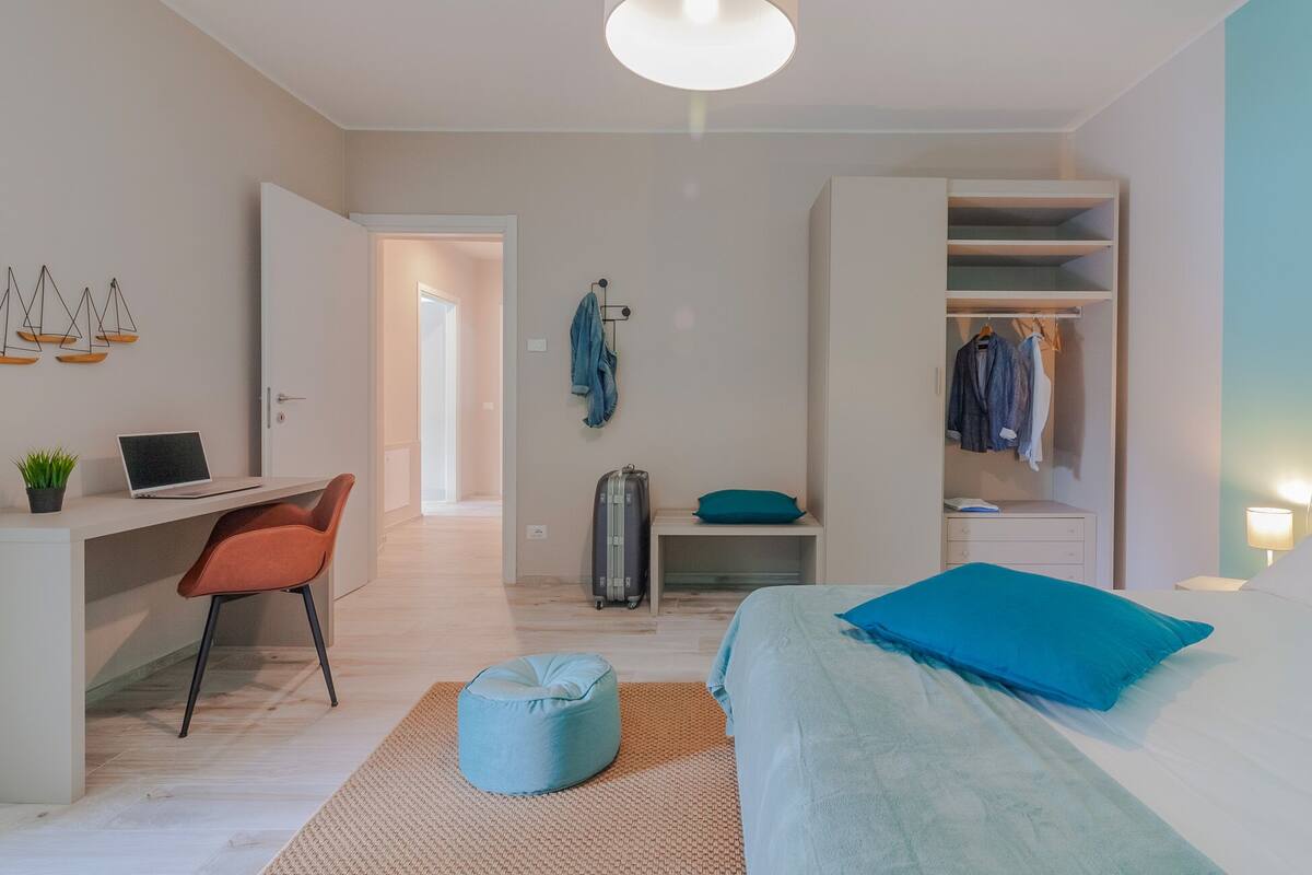 A modern bedroom with a bed, a desk, and a wardrobe.
