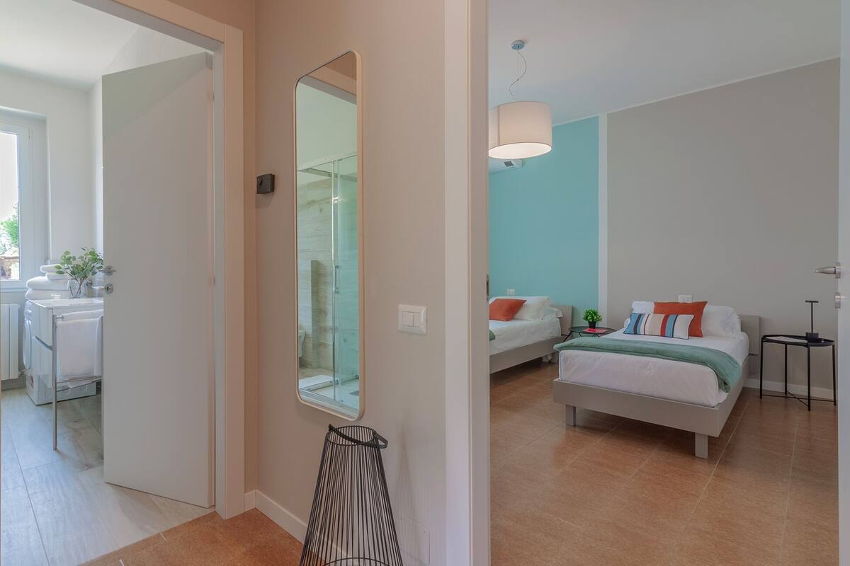 A modern bedroom with a bed, bedside table, and a mirror.