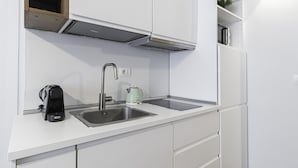 A modern kitchen with white cabinetry, a stainless steel sink, a kettle, and a coffee maker. - Italianway - San Marco 1 (Milan)