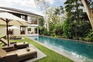 A modern house with a swimming pool, outdoor lounge area, and lush greenery. - Omekali Canggu by Nakula (Canggu)